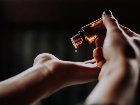 Droping a drop of essential oil from bottle to a hand